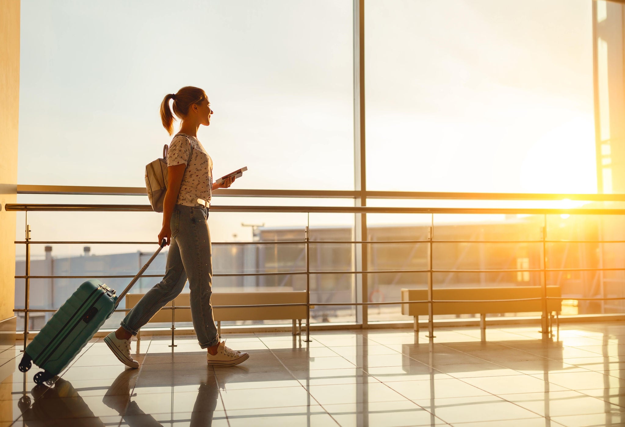 photo-woman-airport-suitcase-travel-waslking-ponytail-phone-min
