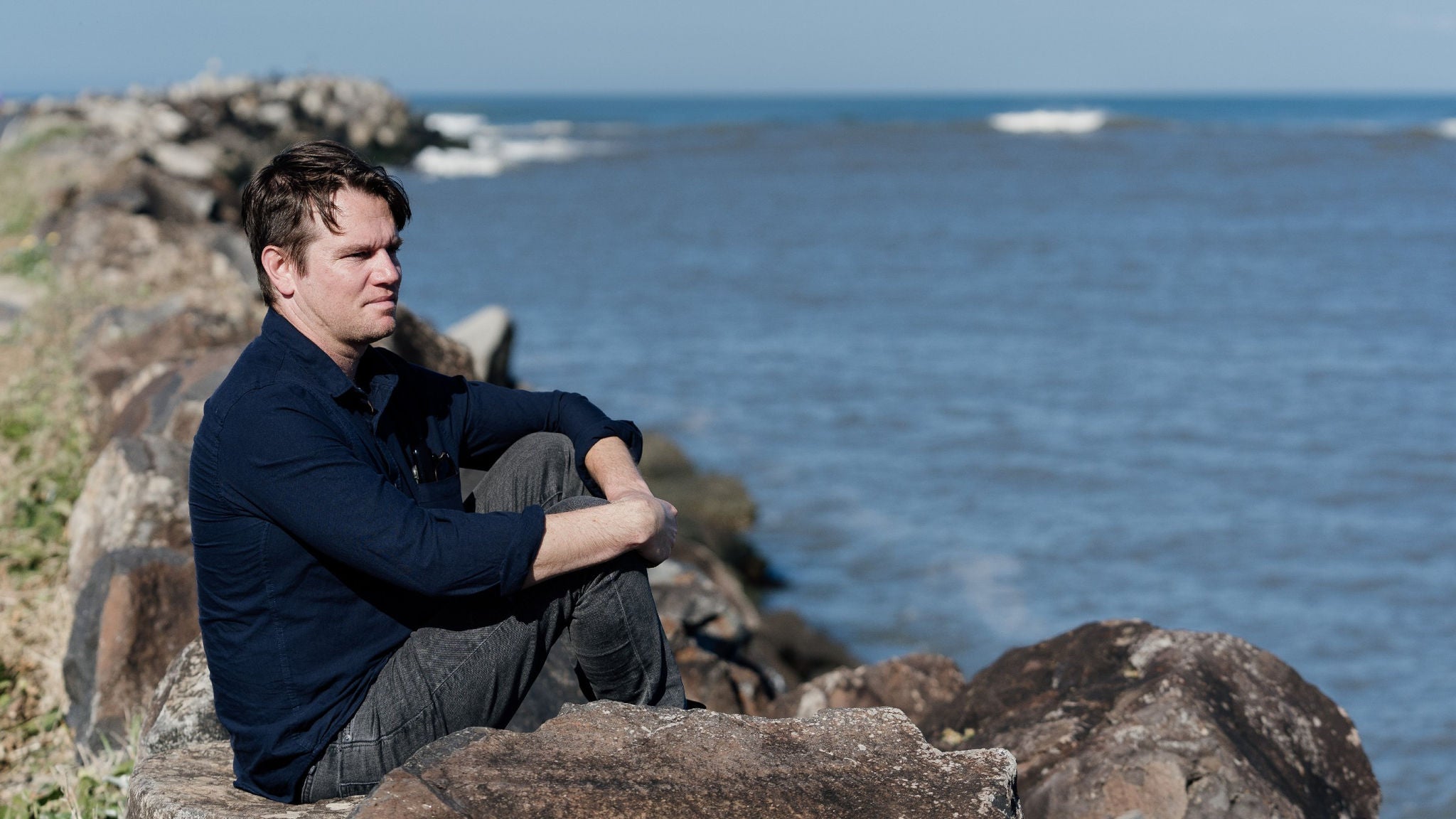 photo-james-wallace-sitting-on-a-rock-looking-out-to-sea