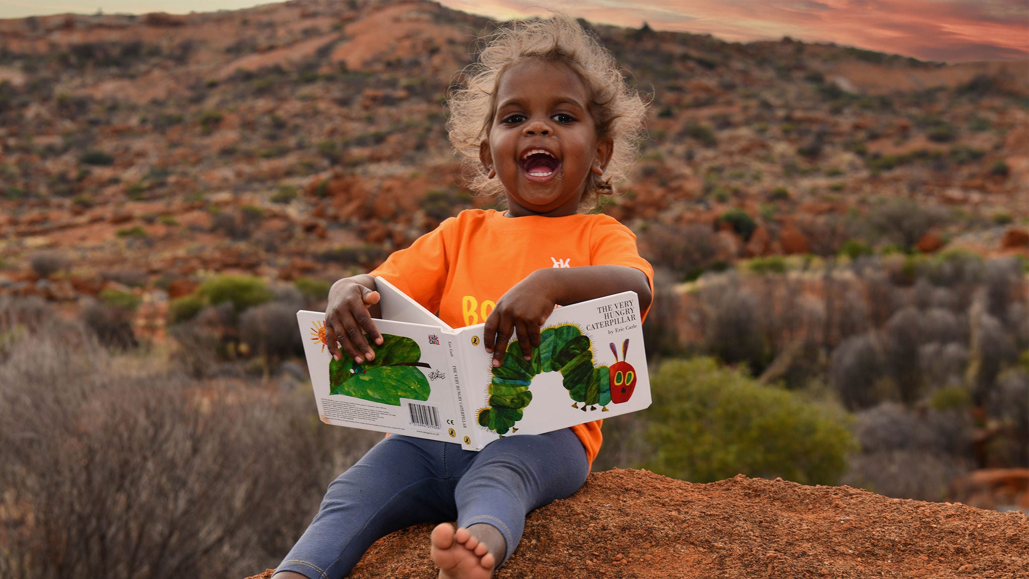 photo-indigenous-child-laughing-holding-book-outback-australia