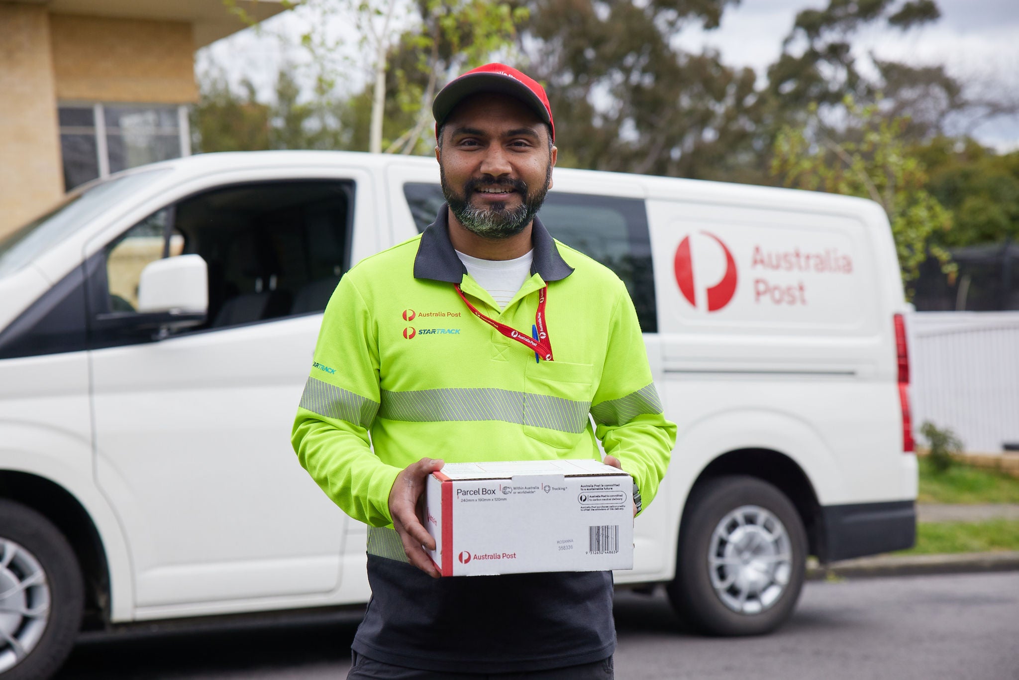 A parcel delivery contractor standing in front of a while delivery van