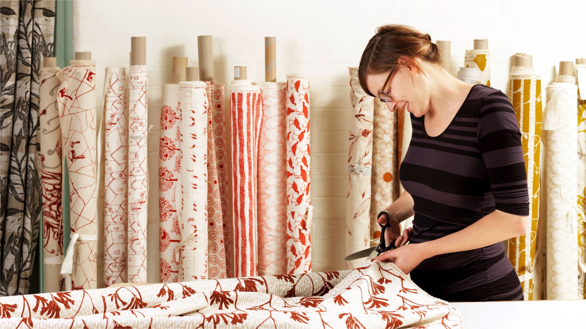photo-woman-cutting-rolls-of-fabric-material