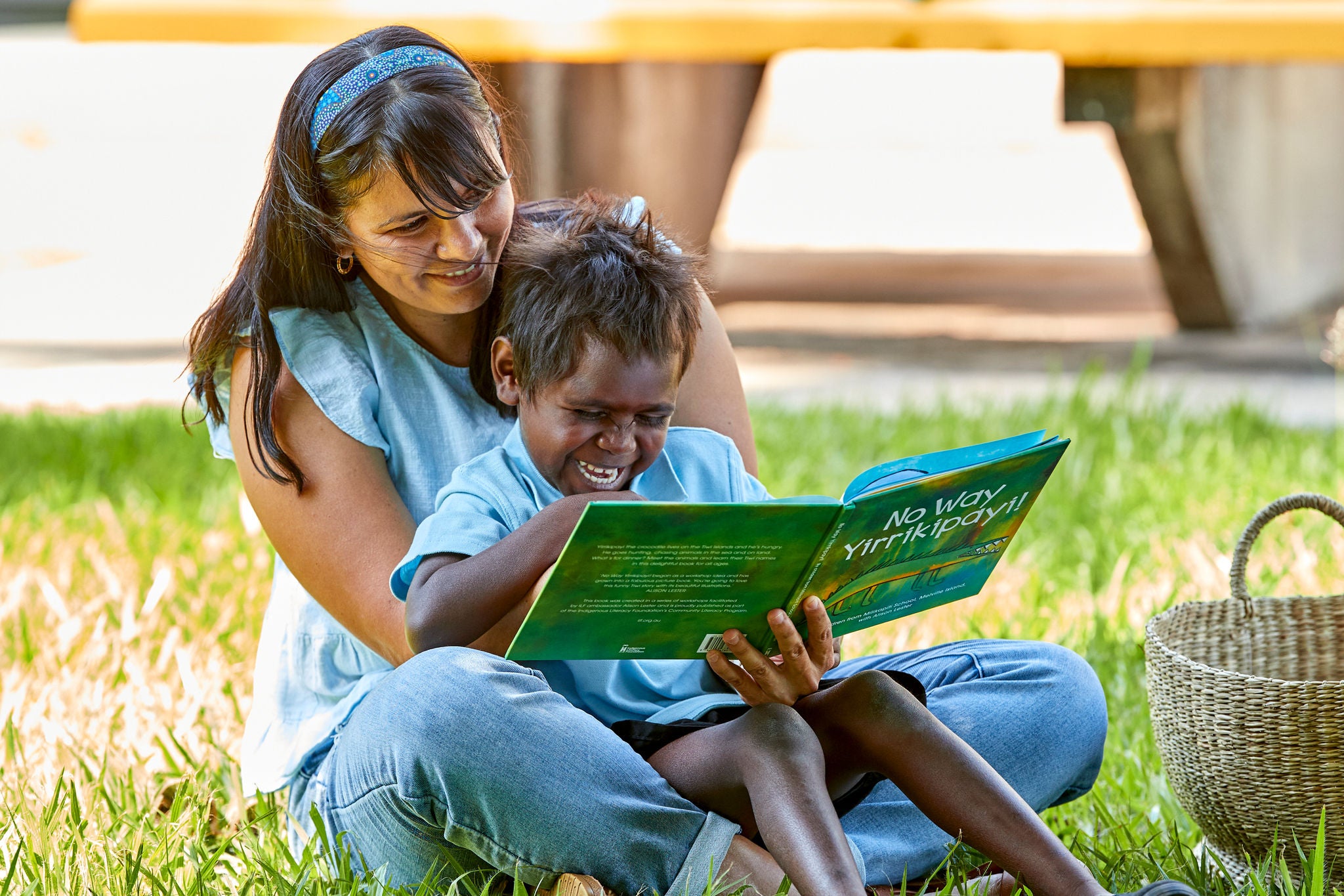 Child sitting in woman's lap and reading book