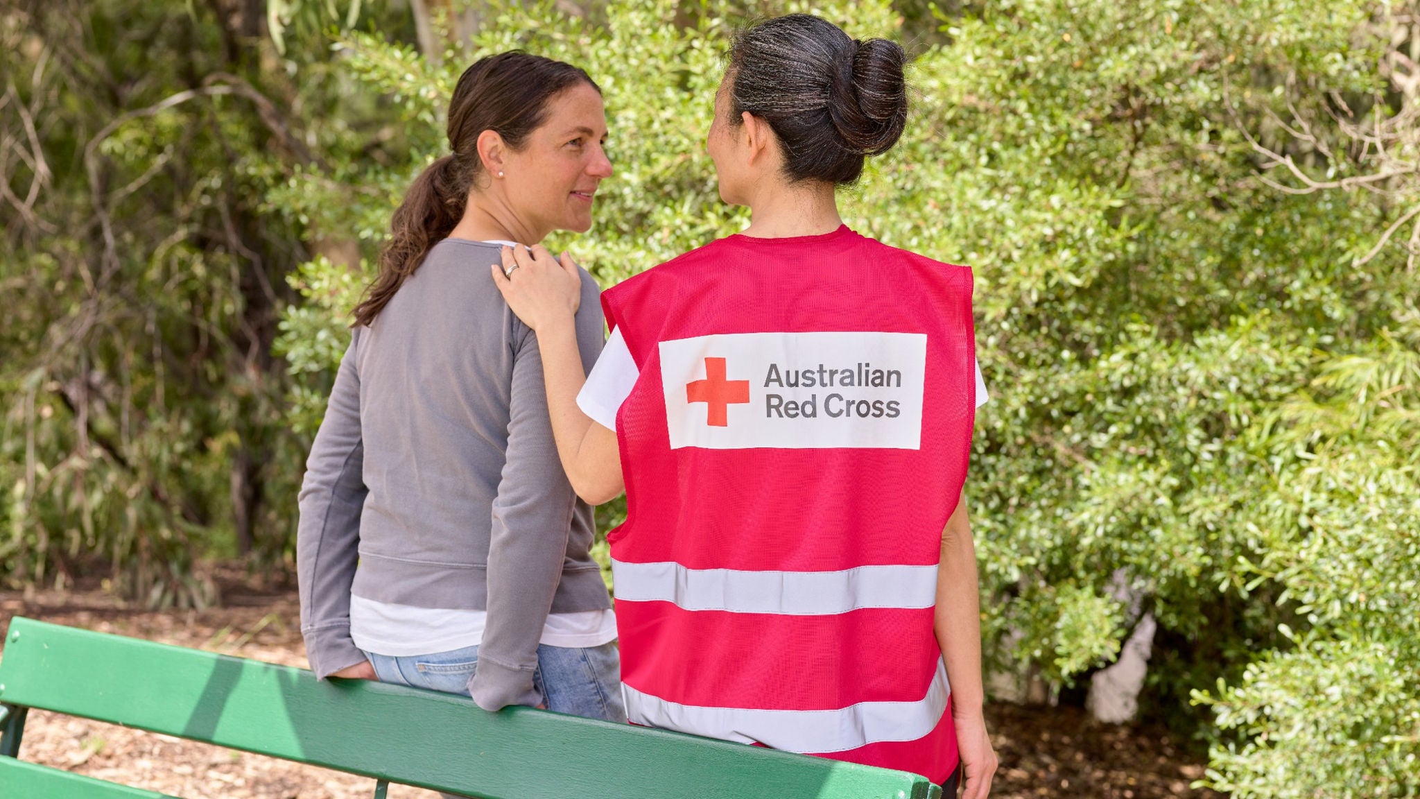 photo-female-red-cross-volunteer-consoling-woman-on-park-bench