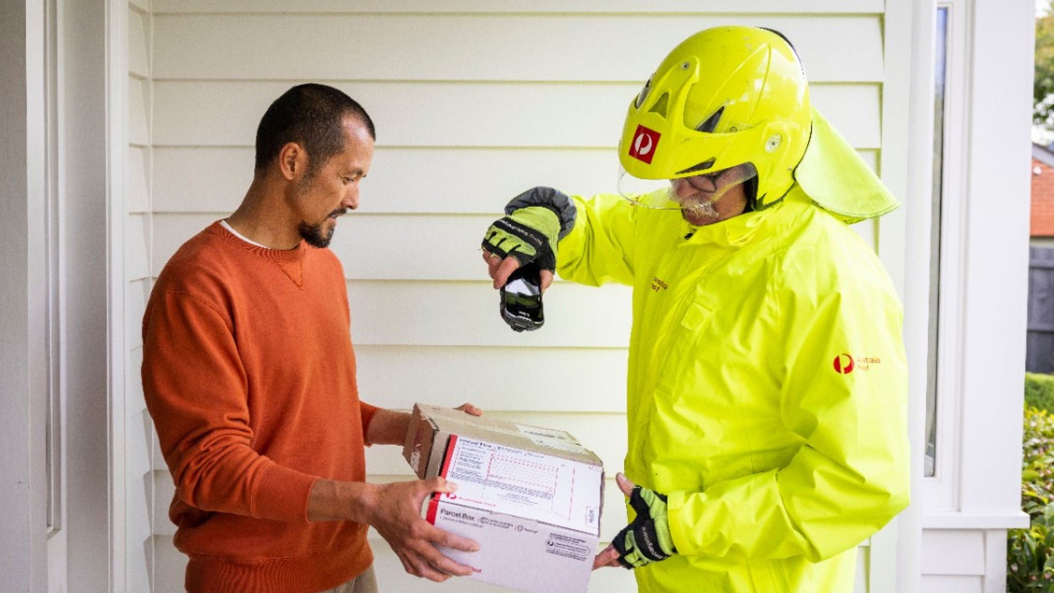 photo man holding parcel while postie scans it