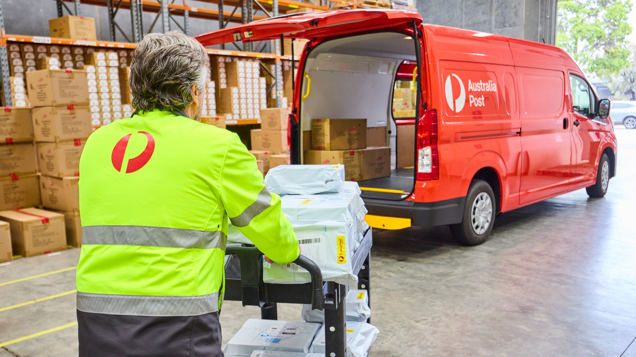 photo-driver-loading-van-pushing-trolley-satchels-parcels-grey-hair
