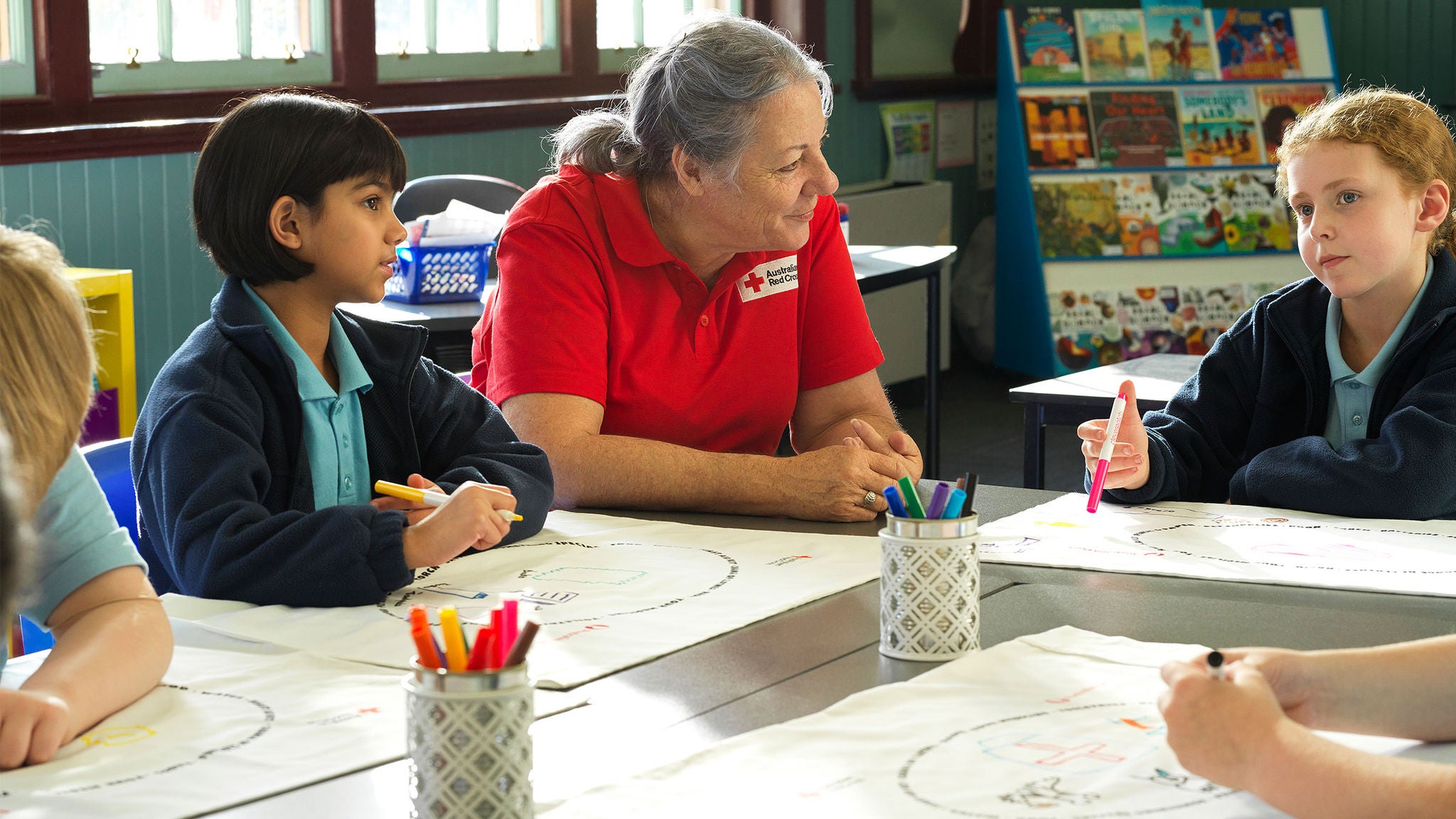 photo-woman-wearing-red-cross-shirt-sitting-table-children