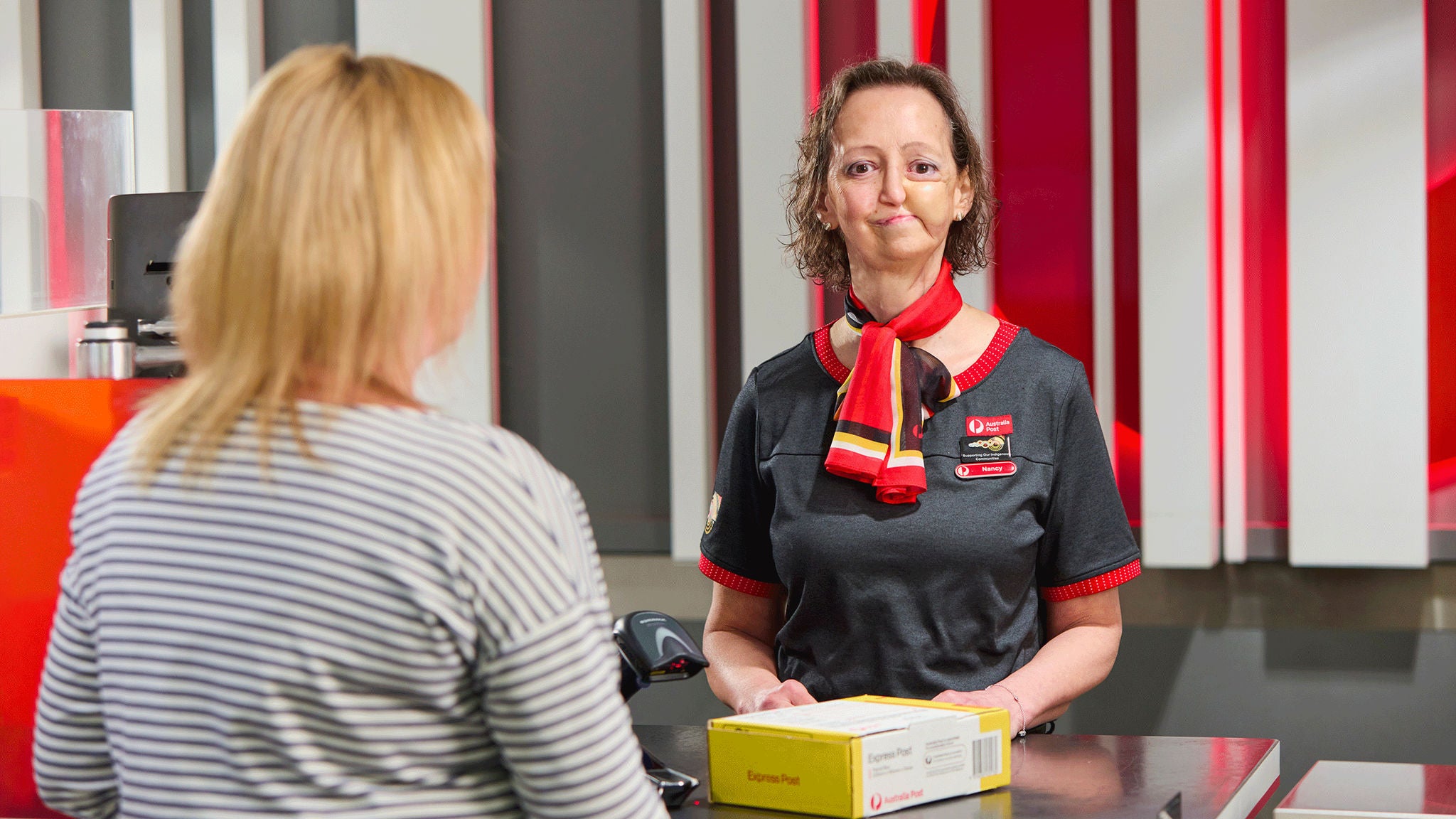 photo-female-retail-employee-at-counter-helping-customer