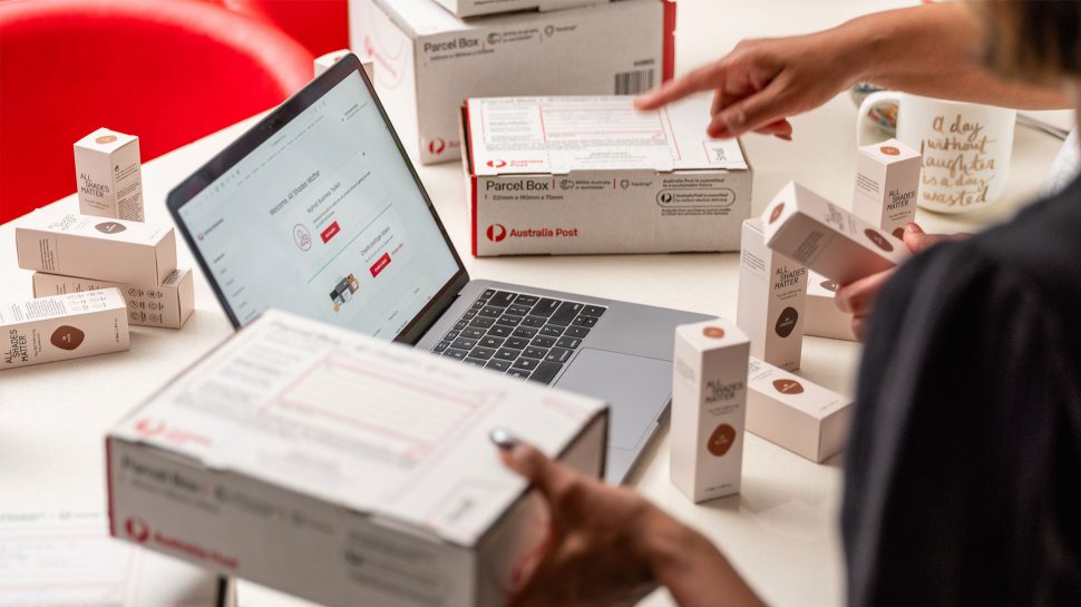 Close up of a table full of make-up products, Austraila Post boxes and a laptop with the screen showing MyPost Business